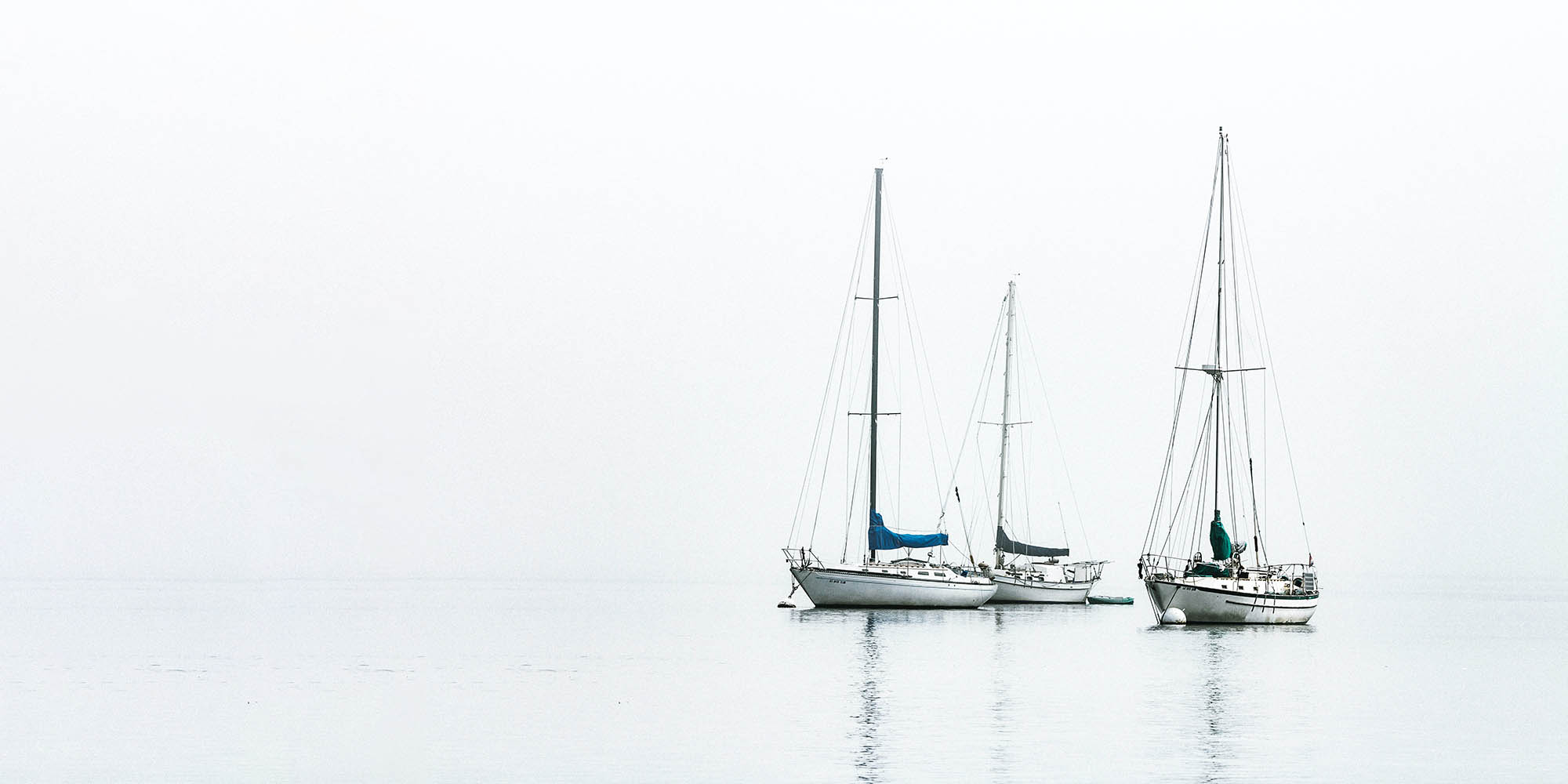 three sailboats on the water